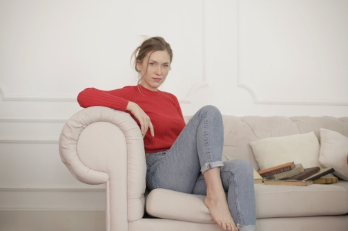 woman-in-red-long-sleeve-shirt-and-denim-jeans-sitting-on-3848056
